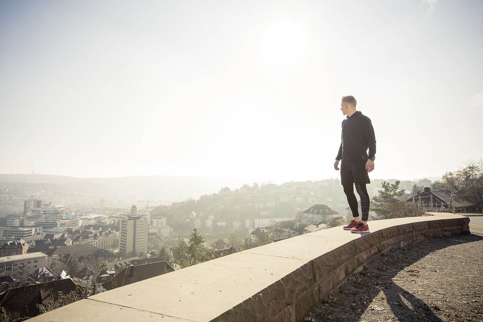Florian Schwab steht auf einer Mauer über Stuttgart im Gegenlicht